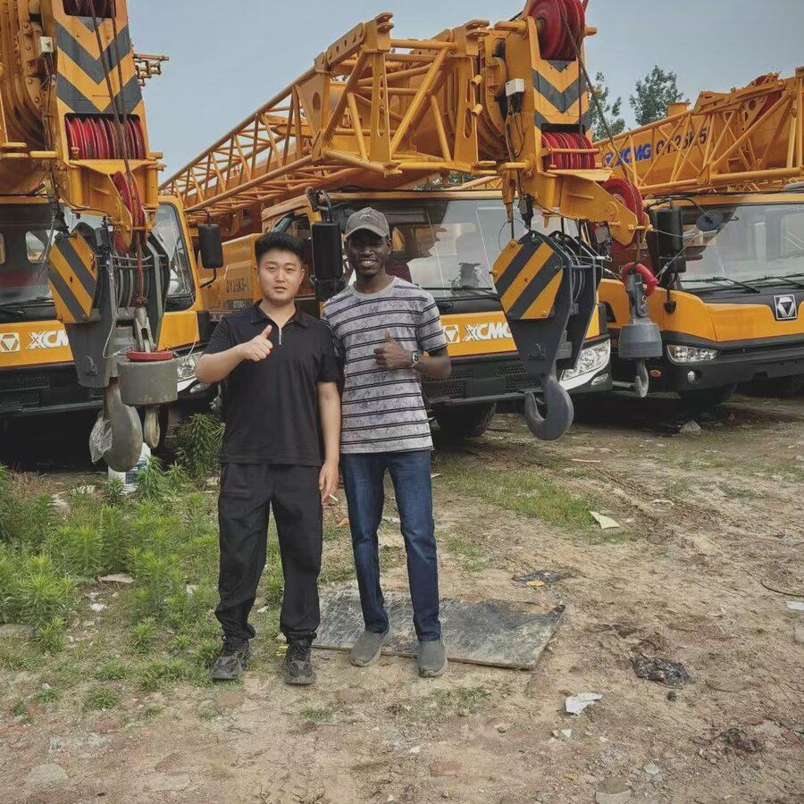 Youman with a Chinese dealer in a yard of mobile cranes and heavy machinery.